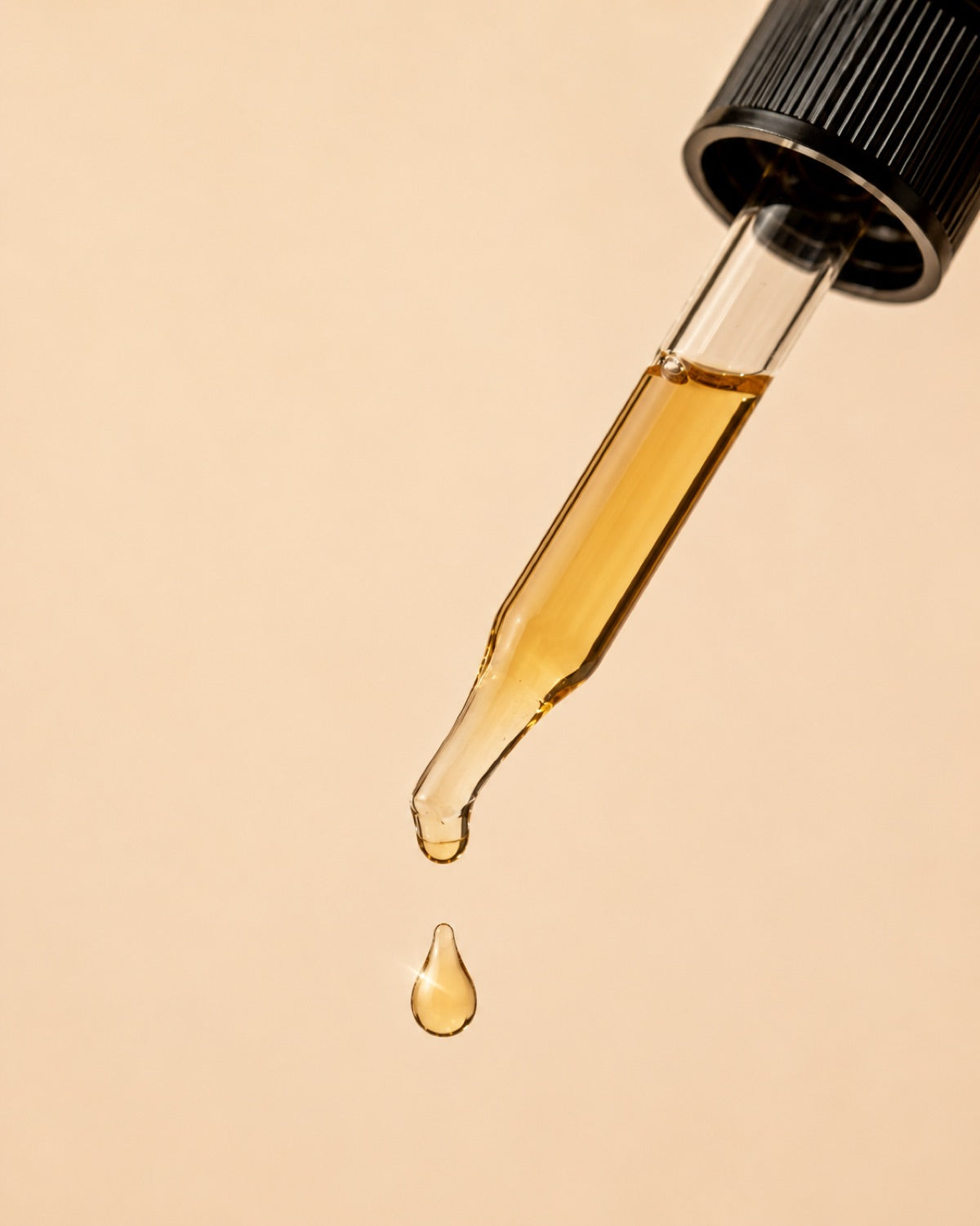 Close-up of golden hair oil on a glass dropper